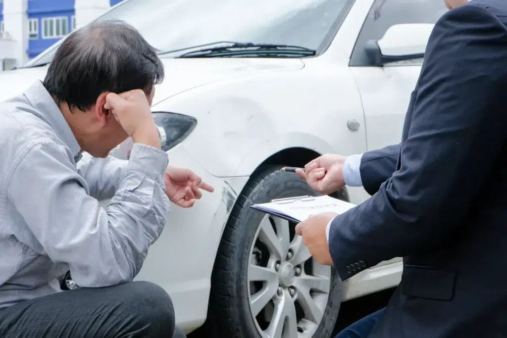 Driver and legal professional review damage to vehicle after auto accident.