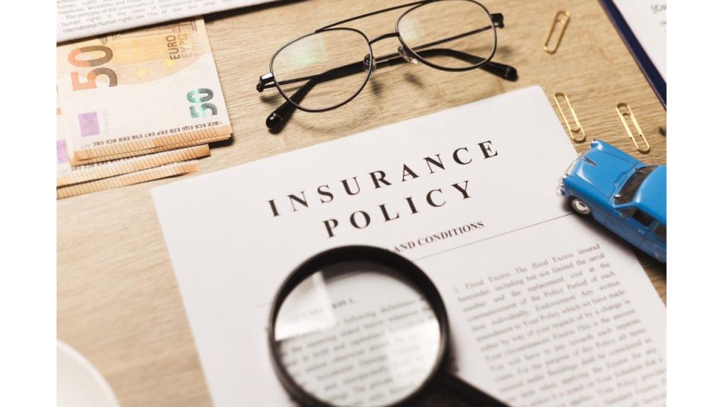 Car Insurance Policy with magnifying glass, toy car, money, and eyeglasses on a desk