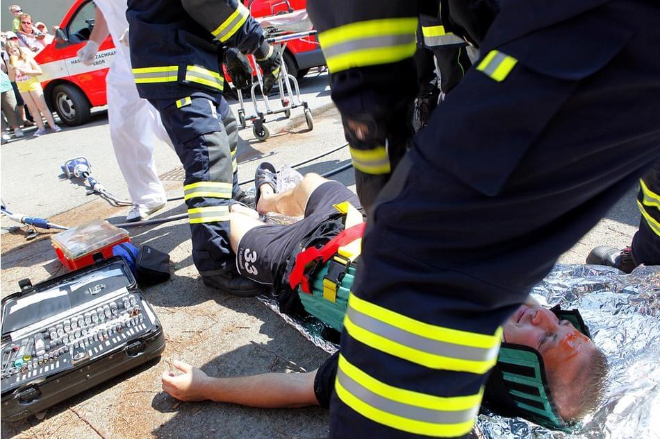 Emergency responders treat an injured man on the ground using a spinal board and neck brace
