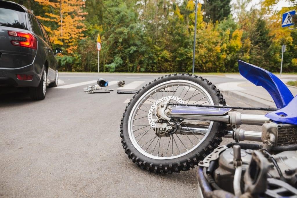 blue motorcycle on the ground near a gray car
