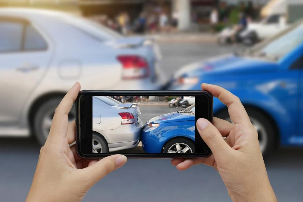 Person taking photos of vehicle damage after a car accident for insurance and legal documentation